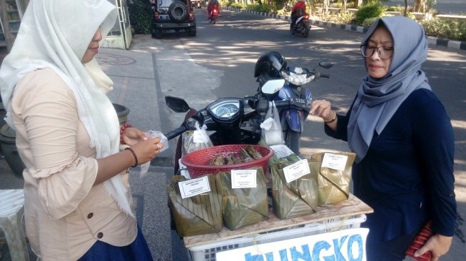 Istiana (kiri) berada di lapaknya di kawasan Gresik Kota Baru, Rabu (15/5/2019). Dalam sehari bisa menjual 40 hingga 50 bungkus Bongko Kopyor selama bulan puasa. (Suara.com/Tofan Kumara)