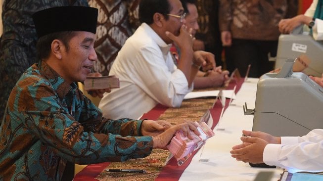 Presiden Joko Widodo (kiri) menyerahkan pembayaran zakat mal kepada petugas di Istana Negara, Jakarta, Kamis (16/5). [ANTARA FOTO/Akbar Nugroho Gumay]