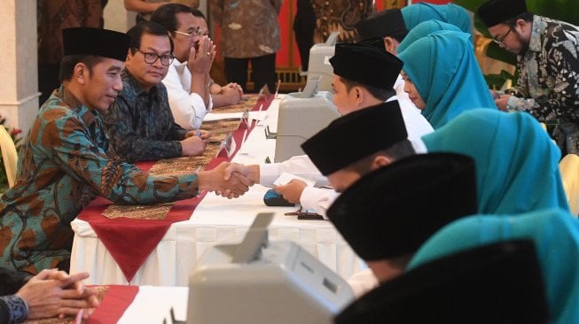 Presiden Joko Widodo (kiri) berjabat tangan dengan petugas usai melakukan pembayaran zakat mal di Istana Negara, Jakarta, Kamis (16/5). [ANTARA FOTO/Akbar Nugroho Gumay]