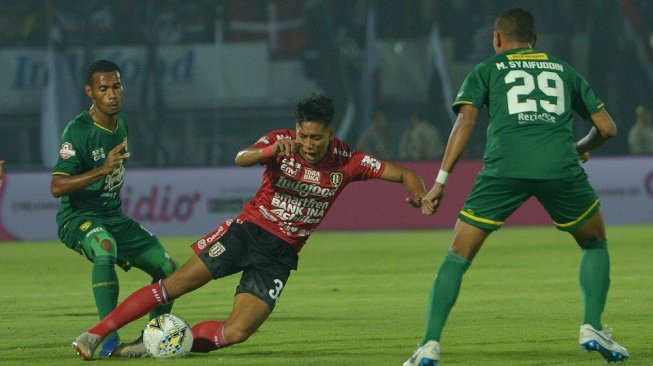 Pesepak bola Bali United Andhika Wijaya (tengah) berebut bola dengan pesepak bola Persebaya Ruben Sanadi (kiri) dalam pertandingan Sepak Bola Liga 1 2019 di Stadion I Wayan Dipta, Gianyar, Bali, Kamis (16/5/2019). ANTARA FOTO/Nyoman Budhiana