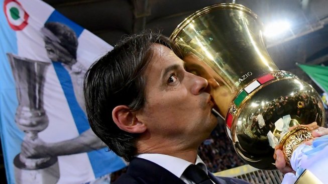 Pelatih Lazio, Simone Inzaghi mencium trofi Coppa Italia usai timnya mengalahkan Atalanta 2-0 pada laga final di Stadio Olimpico, Kamis (16/5/2019) dini hari WIB. [Vincenzo PINTO / AFP]