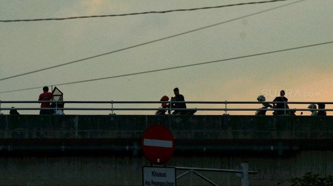 Sejumlah warga menunggu waktu berbuka puasa di Flyover Pasar Rebo, Kamis (16/5). [Suara.com/Muhaimin A Untung]