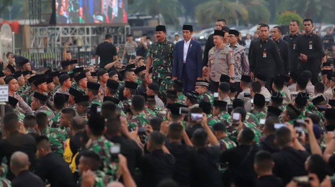 Presiden Joko Widodo (tengah) didampingi Panglima TNI Marsekal TNI Hadi Tjahjanto (kiri) dan Kapolri Jenderal Pol Tito Karnavian (kanan) tiba di lokasi acara buka puasa bersama keluarga besar TNI-Polri dan masyarakat di Jakarta, Kamis (16/5). [Suara.com/Muhaimin A untung]