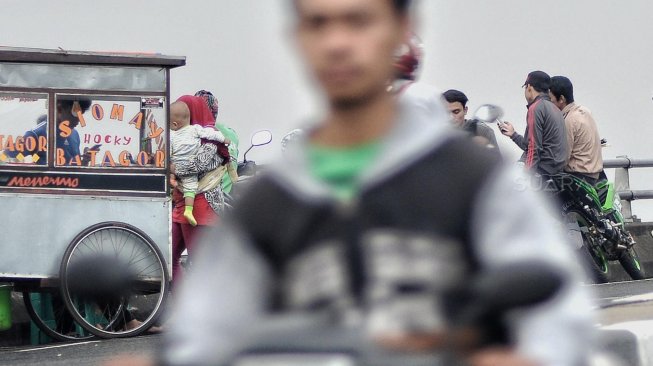 Sejumlah warga menunggu waktu berbuka puasa di Flyover Pasar Rebo, Kamis (16/5). [Suara.com/Muhaimin A Untung]