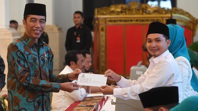 Presiden Joko Widodo (kiri) menerima bukti penyerahan zakat mal usai melakukan pembayaran di Istana Negara, Jakarta, Kamis (16/5). [ANTARA FOTO/Akbar Nugroho Gumay]