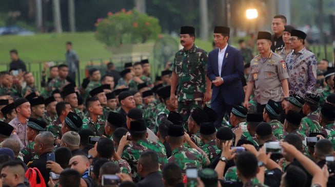 Presiden Joko Widodo (tengah) didampingi Panglima TNI Marsekal TNI Hadi Tjahjanto (kiri) dan Kapolri Jenderal Pol Tito Karnavian (kanan) tiba di lokasi acara buka puasa bersama keluarga besar TNI-Polri dan masyarakat di Jakarta, Kamis (16/5). [Suara.com/Muhaimin A untung]