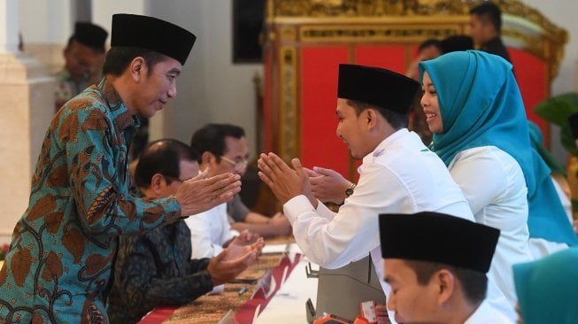 Presiden Joko Widodo (kiri) berjabat tangan dengan petugas usai melakukan pembayaran zakat mal di Istana Negara, Jakarta, Kamis (16/5). [ANTARA FOTO/Akbar Nugroho Gumay]