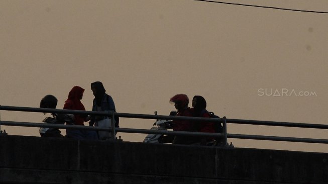 Sejumlah warga menunggu waktu berbuka puasa di Flyover Pasar Rebo, Kamis (16/5). [Suara.com/Muhaimin A Untung]