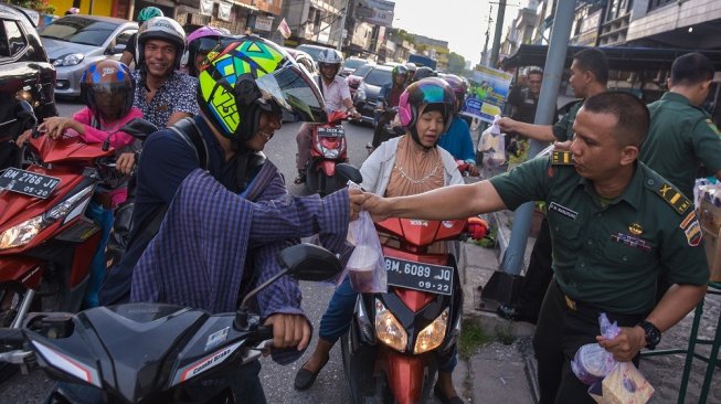 Sejumlah prajurit TNI AD dari Korem 031/Wira Bima membagikan takjil kepada warga di Kota Pekanbaru, Riau, Rabu (8/5/2019). Korem 031/Wira Bima selama bulan puasa membagikan ratusan takjil setiap hari untuk mempererat silaturahmi antara TNI dan masyarakat, guna menciptakan rasa saling menghormati dan lebih peduli sesama pada bulan suci Ramadhan [ANTARA FOTO/FB Anggoro].