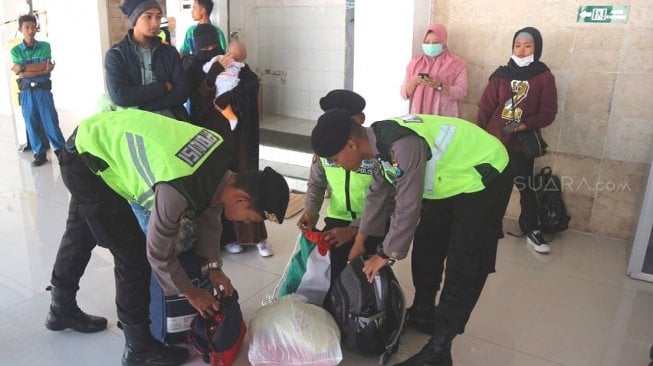  Polisi memeriksa tas penumpang bus jurusan Jakarta di Terminal Bus Patria Blitar, Minggu (19/5/2019). (Suara.com/Agus H)