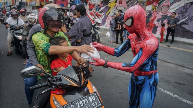 Warga mengenakan kostum superhero Spiderman membagikan takjil kepada pengguna jalan saat kegiatan Bagi-Bagi Takjil Komunitas Cosplay di jalan Gatot Subroto, Solo, Jawa Tengah, Minggu (19/5). [ANTARA FOTO/Mohammad Ayudha]