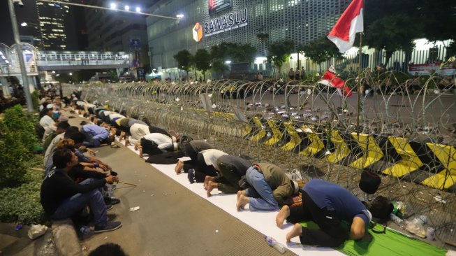 Massa Gerakan Nasional Kedaulatan Rakyat menunaikan shalat Tarawih di sela aksi unjuk rasa di depan Kantor Bawaslu Jakarta, Selasa (21/5). [Suara.com/Muhaimin A Untung]