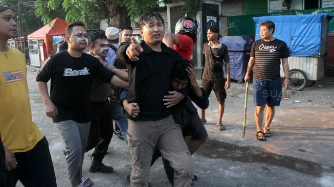 Polisi dan warga menangkap seorang yang diduga provokator pembakaran mobil di Komplek Asrama Brimob, Petamburan, Jakarta, Rabu (22/5). [Suara.com/Arief Hermawan P]