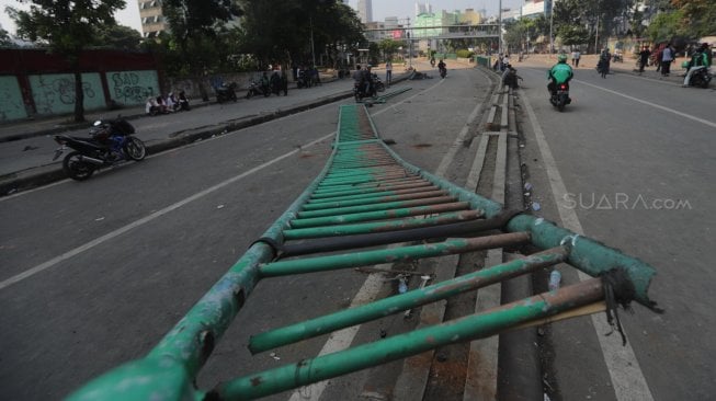 Kendaraan melintas di samping pembatas jalan yang rusak di Kawasan Tanah Abang, Jakarta, Rabu (22/5). [Suara.com/Muhaimin A Untung]