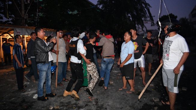 Polisi dan warga menangkap seorang yang diduga menjadi provokator pembakaran mobil di Komplek Asrama Brimob Petamburan, Jakarta, Rabu (22/5/2019). [Antara/Sigid Kurniawan]