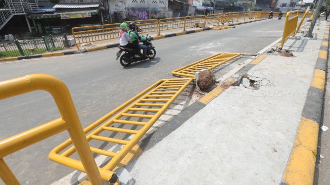 Kendaraan melintas di samping pembatas jalan yang rusak di Kawasan Tanah Abang, Jakarta, Rabu (22/5). [Suara.com/Muhaimin A Untung]