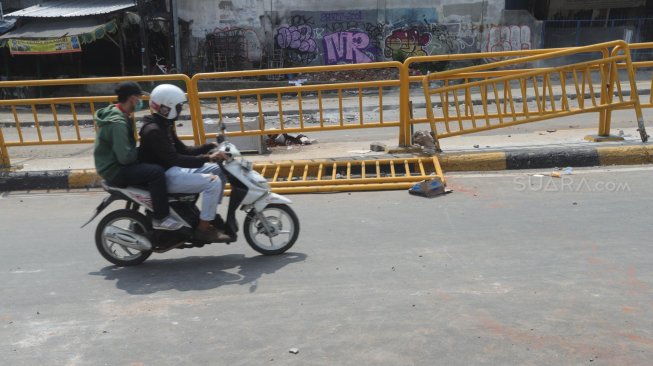 Kendaraan melintas di samping pembatas jalan yang rusak di Kawasan Tanah Abang, Jakarta, Rabu (22/5). [Suara.com/Muhaimin A Untung]