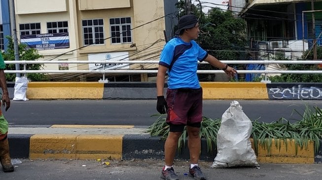 Janes, pria 45 tahun ini sedang membantu petugas Suku Dinas Lingkungan Hidup Kecamatan Palmerah. (Suara.com/Fakhri)