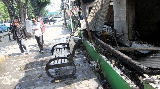 Warga memperhatikan Pos Polisi (Pospol) yang hangus di Jalan Sabang, Jakarta, Kamis (23/5). [Suara.com/Arief Hermawan P]
