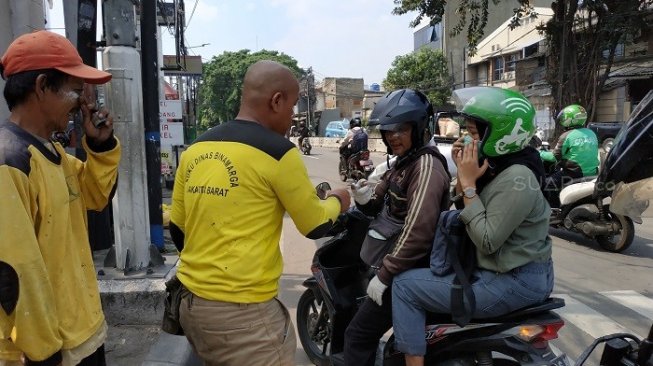 Imbas gas air mata, petugas bagikan pasta gigi ke pengendara di kawasan Slipi. (Suara.com/Fakhri).