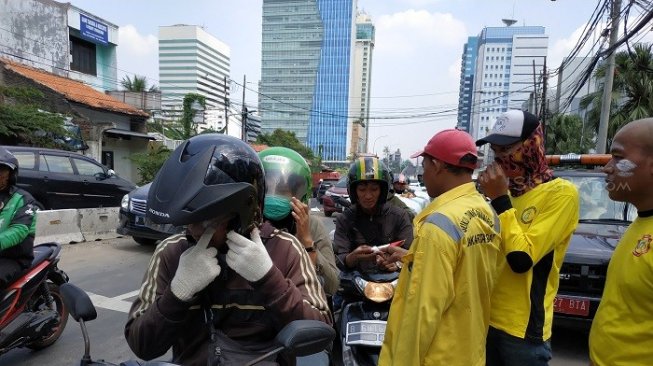 Imbas gas air mata, petugas bagikan pasta gigi ke pengendara di kawasan Slipi. (Suara.com/Fakhri).