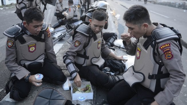 Personel Kepolisian berbuka puasa di tengah mengamankan jalannya aksi unjuk rasa 22 Mei di Jalan Brigjen Katamso, Slipi, Jakarta, Rabu (22/5). Rusuh juga terjadi di bawah flyover. [ANTARA FOTO?M Risyal Hidayat]