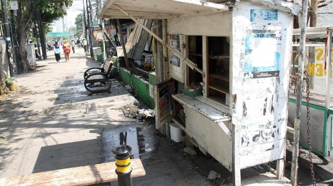 Warga melintas disekitar warung kelontong yang telah kosong di Jalan Sabang, Jakarta, Kamis (23/5). [Suara.com/Arief Hermawan P]