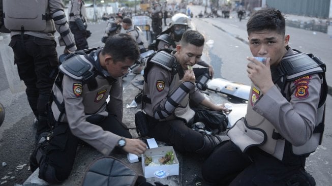 Personel Kepolisian berbuka puasa di tengah mengamankan jalannya aksi unjuk rasa 22 Mei di Jalan Brigjen Katamso, Slipi, Jakarta, Rabu (22/5). [ANTARA FOTO?M Risyal Hidayat]