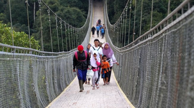 Wisatawan melintasi Jembatan Gantung Situ Gunung (Suspension Bridge Situ Gunung) di Kawasan Taman Nasioal Gunung Gede Pangrango (TNGGP), Kadudampit, Kabupaten Sukabumi, Jawa Barat, Jumat (25/5). [Suara.com/Arief Hermawan P]