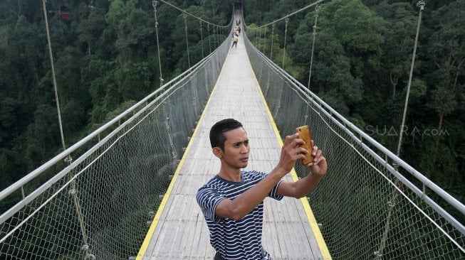 Wisatawan selfie di Jembatan Gantung Situ Gunung (Suspension Bridge Situ Gunung) di Kawasan Taman Nasioal Gunung Gede Pangrango (TNGGP), Kadudampit, Kabupaten Sukabumi, Jawa Barat, Jumat (25/5). [Suara.com/Arief Hermawan P]