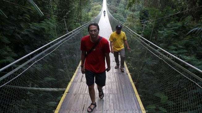 Wisatawan melintasi Jembatan Gantung Situ Gunung (Suspension Bridge Situ Gunung) di Kawasan Taman Nasioal Gunung Gede Pangrango (TNGGP), Kadudampit, Kabupaten Sukabumi, Jawa Barat, Jumat (25/5). [Suara.com/Arief Hermawan P]