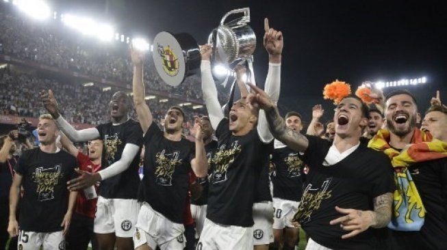 Rodrigo Moreno mengangkat trofi bersama para pemain Valencia lainnya merayakan kemenangan menjadi juara Copa del Rey setelah mengalahkan Barcelona di final. JOSE JORDAN / AFP