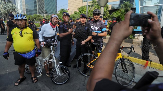 Warga berfoto dengan petugas polisi di Gedung Badan Pengawas Pemilu (Bawaslu) saat Hari Bebas Kendaraan Bermotor di kawasan Sarinah, Jakarta, Minggu (26/5). [Suara.com/Muhaimin A Untung]