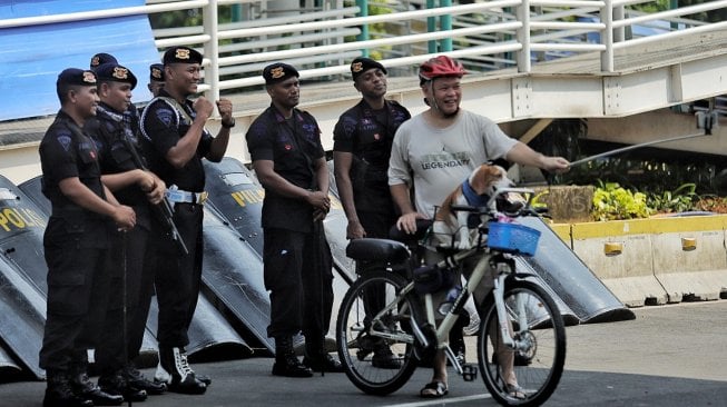 Warga berfoto dengan petugas polisi di Gedung Badan Pengawas Pemilu (Bawaslu) saat Hari Bebas Kendaraan Bermotor di kawasan Sarinah, Jakarta, Minggu (26/5). [Suara.com/Muhaimin A Untung]