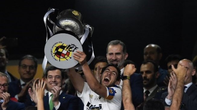 Gelandang Valencia Daniel Parejo mengangkat trofi Copa del Rey setelah mengalhakan Barcelona di final. PAU BARRENA / AFP