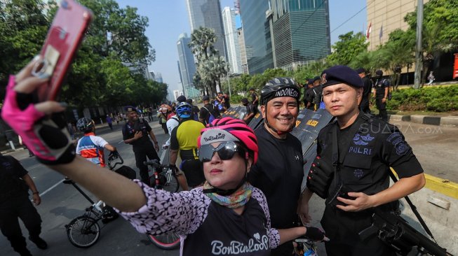 Warga berfoto dengan petugas polisi di Gedung Badan Pengawas Pemilu (Bawaslu) saat Hari Bebas Kendaraan Bermotor di kawasan Sarinah, Jakarta, Minggu (26/5). [Suara.com/Muhaimin A Untung]