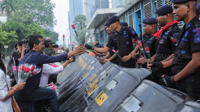 Sejumlah anggota komunitas Spartan Nusantara memberi bunga ke petugas kepolisian saat aksi dukungan di depan kantor Bawaslu, Jakarta, Minggu (26/5). [Suara.com/Muhaimin A Untung]