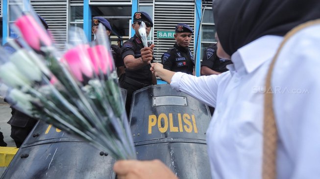 Sejumlah anggota komunitas Spartan Nusantara memberi bunga ke petugas kepolisian saat aksi dukungan di depan kantor Bawaslu, Jakarta, Minggu (26/5). [Suara.com/Muhaimin A Untung]