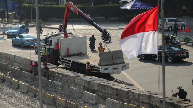 Sejumlah petugas tengah menggulung kawat berduri dan mengangkat barrier beton yang menutupi Jalan MH Thamrin depan kantor Bawaslu, Jakarta, Senin (27/5). [Suara.com/Muhaimin A Untung]