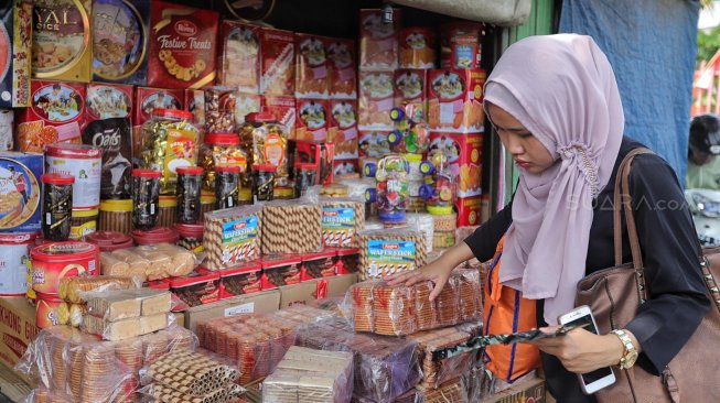 Sejumlah calon pembeli memilih kue kering dalam kemasan di lapak penjual kue musiman di depan pabrik Khong Guan, Jalan Raya Bogor Km. 26, Ciracas, Jakarta Timur, Senin (27/5). [Suara.com/Muhaimin A Untung]