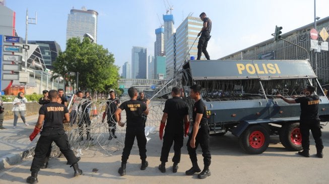 Sejumlah petugas tengah menggulung kawat berduri dan mengangkat barrier beton yang menutupi Jalan MH Thamrin depan kantor Bawaslu, Jakarta, Senin (27/5). [Suara.com/Muhaimin A Untung]