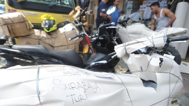 Pekerja merapikan sepeda motor yang akan dikirim di Stasiun Pasar Senen, Jakarta, Rabu (29/5). [Suara.com/Muhaimin A Untung]
