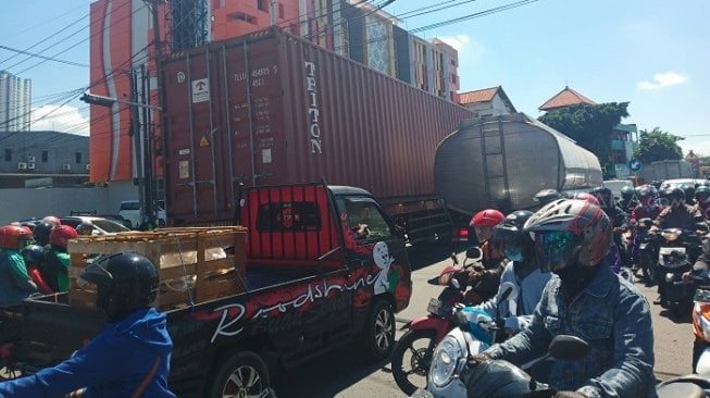 Penampakan truk barang yang melintas di Jalan Karangpilang, Surabaya. (Suara.com/Ali).