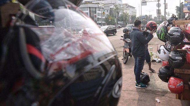 Pengunjung melihat jajaran helm yang dijual oleh pedagang di Jl Matraman, Jakarta, Jumat (31/5). [Suara.com/Muhaimin A Untung]