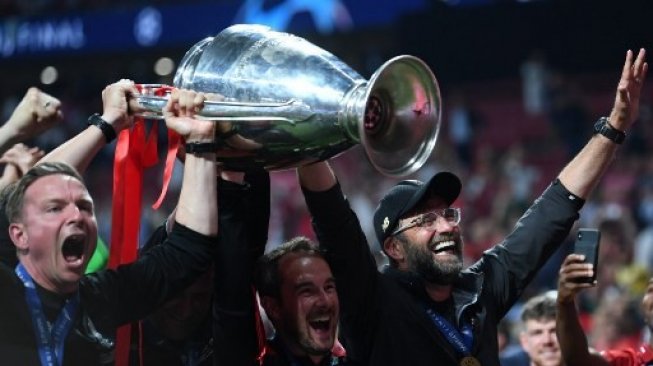 Jurgen Klopp dan staf kepelatihan Liverpool mengangkat trofi Liga Champions usai mengalahkan Tottenham Hotspur 2-0 di laga final. (PAUL ELLIS / AFP)