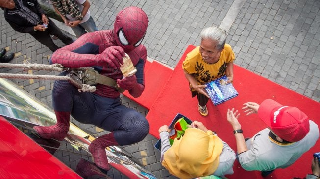 Panitia dari Keluarga Alumni Universitas Gadjah Mada (Kagama) berkostum superhero Spiderman membagikan sarung dan uang fitrah kepada warga pada kegiatan Berbagi Sarung Untuk Sahabat di Balaikota Solo, Jawa Tengah, Senin (3/6). [ANTARA FOTO/Mohammad Ayudha]