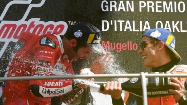 Pebalap Repsol Marc Marquez menyemprotkan champagne ke wajah juara MotoGP Italia 2019, Danilo Petrucci (kiri) saat melakukan selebrasi di podium. Tiziana FABI / AFP