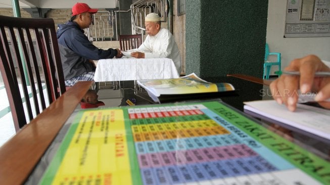 Umat muslim melaksanakan pembayaran Zakat Fitrah di masjid Jami Nurul Islam, Pangkalan Jati, Depok, Jawa Barat, Selasa (4/6). [Suara.com/Arief Hermawan P]