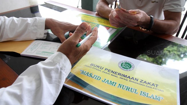 Umat muslim melaksanakan pembayaran Zakat Fitrah di masjid Jami Nurul Islam, Pangkalan Jati, Depok, Jawa Barat, Selasa (4/6). [Suara.com/Arief Hermawan P]