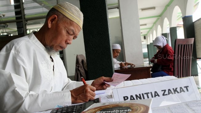 Umat muslim melaksanakan pembayaran Zakat Fitrah di masjid Jami Nurul Islam, Pangkalan Jati, Depok, Jawa Barat, Selasa (4/6). [Suara.com/Arief Hermawan P]